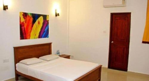a bedroom with a bed and a painting on the wall at OYO 246 Roy Villa Beach Hotel in Beruwala