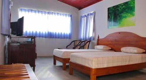 a bedroom with two beds and a tv and a window at OYO 246 Roy Villa Beach Hotel in Beruwala