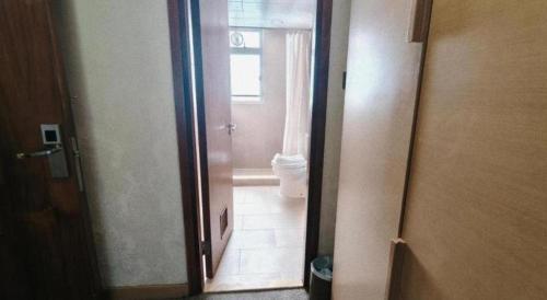 a bathroom with a door leading to a bathroom with a toilet at H1 Hotel in Hong Kong