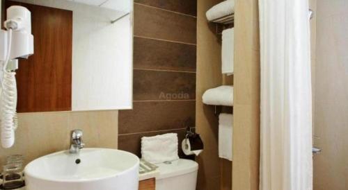 a bathroom with a sink and a toilet and towels at H1 Hotel in Hong Kong