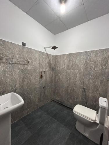 a bathroom with a white toilet and a sink at SJ7 Guest House in Mirissa