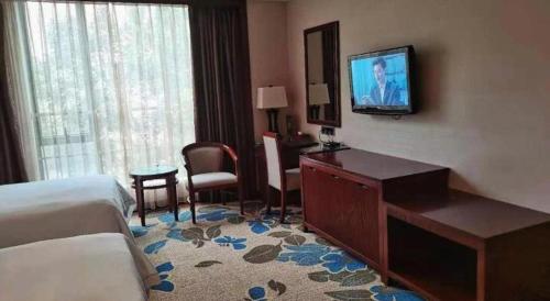 a hotel room with a bed and a television on the wall at Dong Cheng Hotel in Shunde