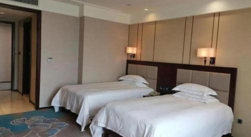 two beds in a hotel room with white sheets at Dong Cheng Hotel in Shunde
