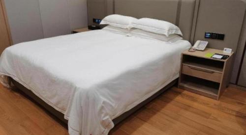 a bed with white sheets and pillows on it at Dong Cheng Hotel in Shunde