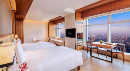 a hotel room with a bed and a desk with a view at AOLUGUYA in Harbin