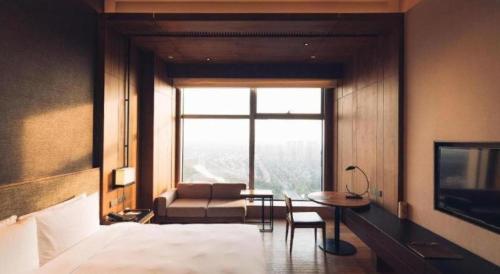 a bedroom with a bed and a couch and a table at AOLUGUYA in Harbin