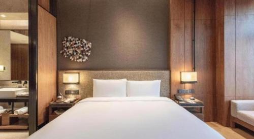 a bedroom with a large white bed and two lamps at AOLUGUYA in Harbin