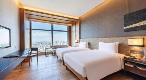two beds in a hotel room with a view of the city at AOLUGUYA in Harbin