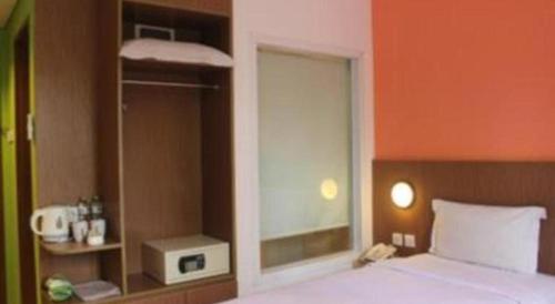 a bedroom with a large bed with a window and a phone at Pomelotel Patra Kuningan Jakarta in Jakarta