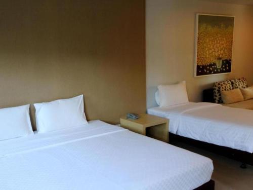 a hotel room with two beds and a table at The One Residence Hotel in Bangkok