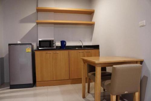 a small kitchen with a table and a refrigerator at The One Residence Hotel in Bangkok