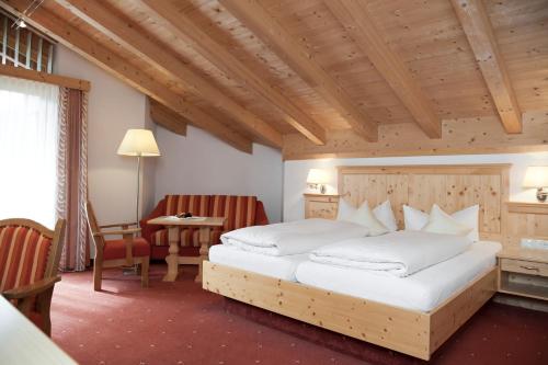 a bedroom with a large bed and a table and chairs at Hotel Troschana in Flirsch