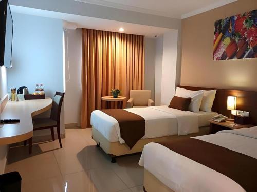 a hotel room with two beds and a desk at Bogor Valley Hotel in Bogor