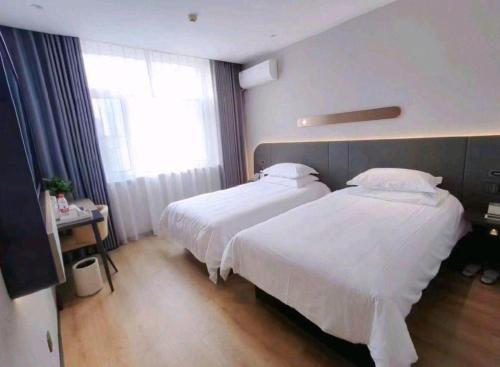 a hotel room with two beds and a window at Jinjiang Inn Changchun Xi An Avenue Branch in Changchun