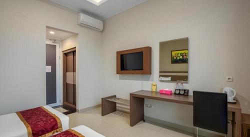 a hotel room with a desk and a tv at Raffleshom Hotel in Bandung