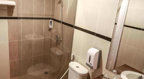 a small bathroom with a toilet and a shower at Raffleshom Hotel in Bandung