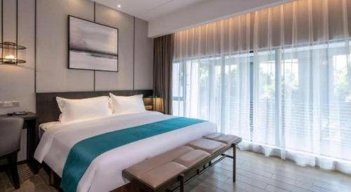 a bedroom with a large bed and a large window at H Life Hotel Nanshan Branch in Shenzhen