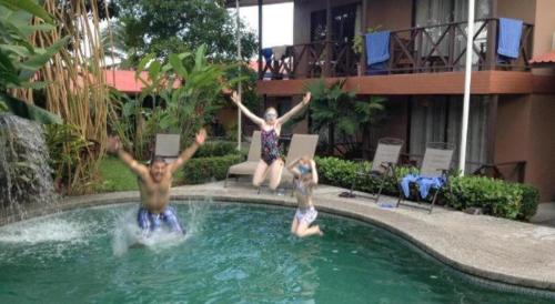 two people are jumping in a swimming pool at Hotel Bijagua in Fortuna