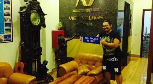 a man holding a sign in a room with a clock at Viet Village Hotel in Hanoi