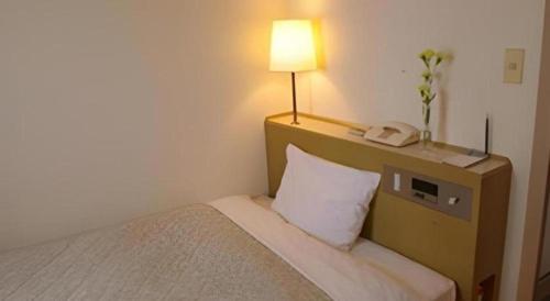 a hotel room with a bed with a lamp and a phone at Isehara Green Palace Hotel in Isehara
