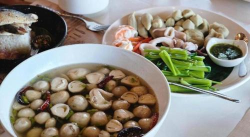 a bowl of mushrooms and vegetables on a table at The Buffalo Amphawa in Samut Songkhram