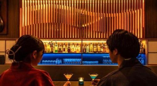 two women standing in front of a bar with drinks at Luxury Wa Hotel Kaze No Kaori in Ito