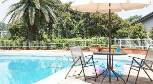a table and chairs with an umbrella next to a pool at Hotel Shofuen in Toyohashi