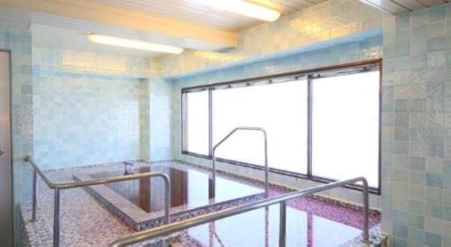 an empty bathroom with a glass window and ailed floor at Hotel Naito Kofu Showa in Kofu