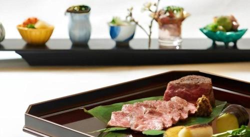 a plate of meat and fruit on a table at Nippondaira Hotel in Shizuoka