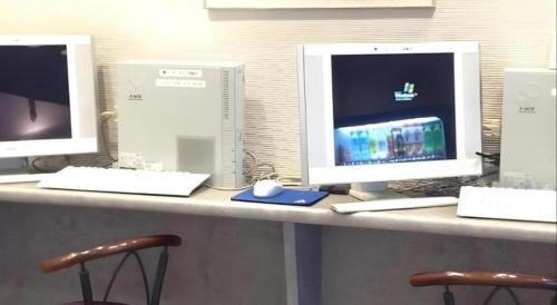 a desk with three computer monitors on top of it at Alpha Hotel Tokushima in Tokushima