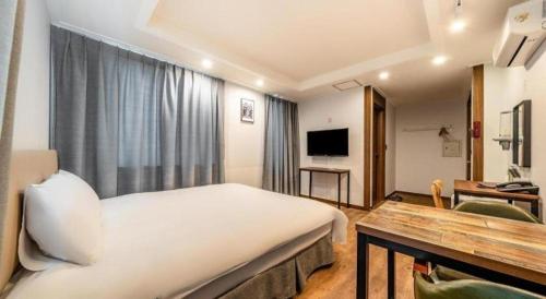a hotel room with a large bed and a television at Check Inn Hotel in Jeju