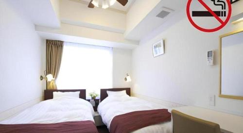 a room with three beds and a no smoking sign at Hotel Shimbashi Sambankan in Tokyo