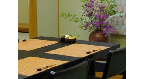 a table with two chairs and a vase with purple flowers at Kyoto Keburikawa Hotel in Kameoka