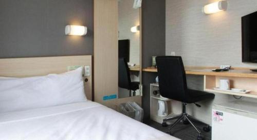 a hotel room with a bed and a desk and chairs at Super Hotel Arai-Niigata in Myoko