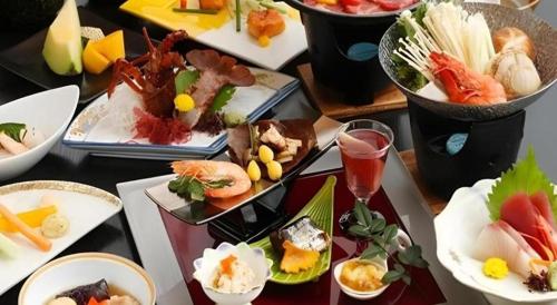 a table topped with plates of sushi and food at Shirako New Seaside Hotel in Shirako