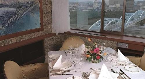 a dining room with a table with flowers on it at Gunma Royal Hotel in Maebashi