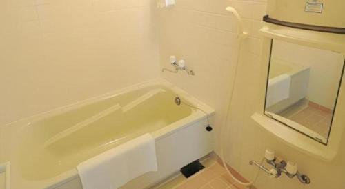 a white bathroom with a tub and a mirror at Hotel Thida No Sato in Miyako Island