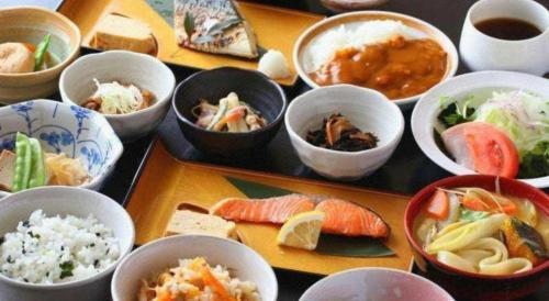 a table topped with bowls of different types of food at Centia Hotel Naito in Kofu