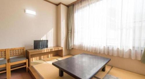 a living room with a coffee table and a window at Hirayu Prince Hotel in Takayama