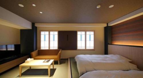 a bedroom with two beds and a couch and a table at Suigetsurou Hotel in Takaoka