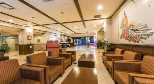 a lobby with chairs and tables and a painting on the wall at Centrale Hotel Kyotango in Kyotango