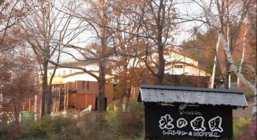 a black dumpster with writing on it in front of trees at Auberge Kitano Dandan in Abashiri