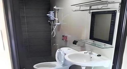 a bathroom with a sink and a toilet and a mirror at Admiral Hotel in Sitiawan