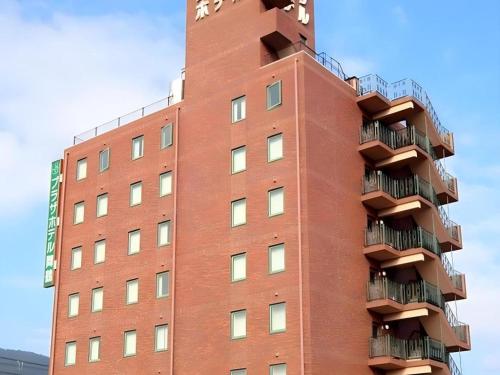 a red brick building with balconies on it at APA Hotel Nishimaizuruekimae in Maizuru