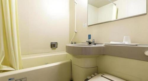 a bathroom with a sink and a toilet and a mirror at APA Hotel Nishimaizuruekimae in Maizuru