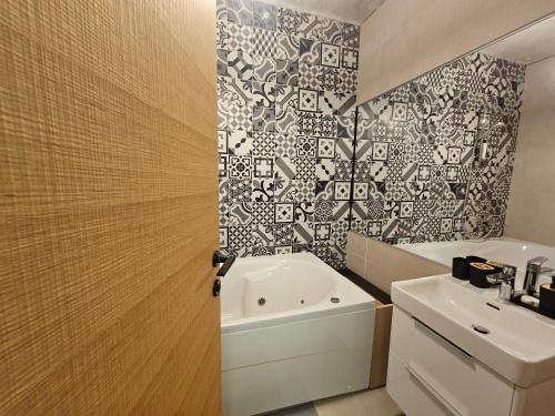 un bagno con lavandino bianco e parete di piastrelle bianche e nere di SUITE 74 apartment Šibenik Finnish sauna & underground garage parking a Šibenik