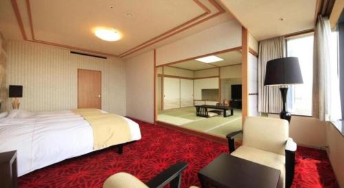 a bedroom with a large bed and a living room at Centurion Hotel Technoport Fukui- Artificial Radium Hot Spring in Sakai