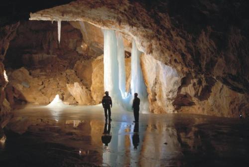 two people walking through a cave with ice formations at Rooms Pevc & Hostel Ljubno ob Savinji in Ljubno