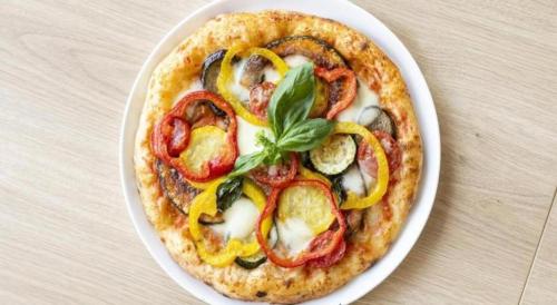 a pizza on a white plate on a table at Goto Tsubaki Hotel in Goto