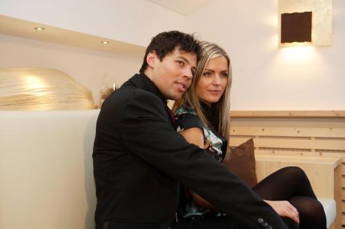 a man and a woman sitting on a couch at Romantik Villa Cesanueva in Selva di Val Gardena